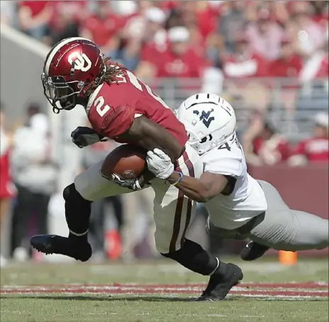  ?? Associated Press ?? West Virginia’s Josh Norwood tries to hang on to Oklahoma receiver CeeDee Lamb Saturday in Norman, Okla. The No. 5 Sooners handed the Mountainee­rs their third loss in a row, 52-14.