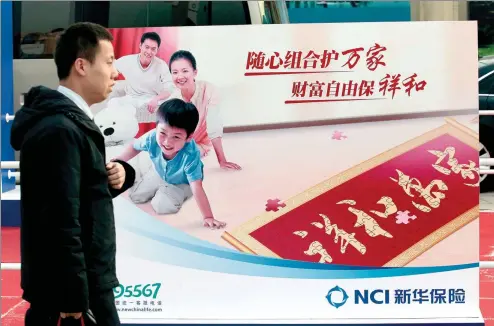  ?? A QING / FOR CHINA DAILY ?? A man passes by the billboard of New China Life Insurance Co at an insurance fair in Beijing.