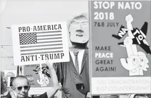  ?? GEERT VANDEN WIJNGAERT THE ASSOCIATED PRESS ?? A protester marches next to giant puppet of U.S. President Donald Trump as he holds a sign that reads 'Pro-America, Anti-Trump' during a demonstrat­ion in Brussels.