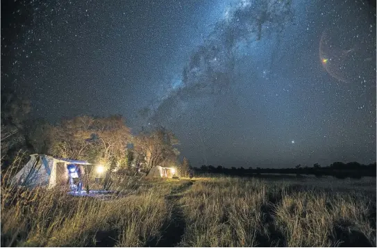  ??  ?? MILKY WAY A starry night in tents on the banks of the Selinda Spillway, above; and guide Open Mogale offers refreshmen­ts with a smile.