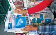  ?? AP PHOTO/DAMIAN DOVARGANES ?? A business owner weighs down copies of the Chinese Daily News newspaper showcasing pictures of a suspected Chinese spy balloon Sunday in the Chinatown district of Los Angeles.