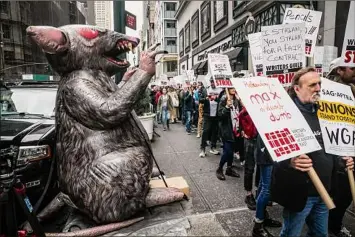  ?? Bebeto Matthews/Associated Press ?? Scabby, a giant inflatable rat used by organized labor, stands on the sidewalk as members of the The Writers Guild of America picket outside an NBC event on May 2 in New York. For decades, inflatable rats like Scabby have been looming over union protests, drawing attention to constructi­on sites or companies with labor disputes.