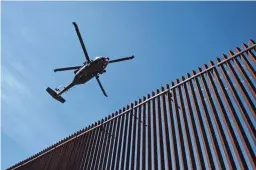  ?? GUILLERMO ARIAS/GETTY IMAGES ?? A U.S. Border Patrol helicopter flies over the U.S.-Mexico border fence as President Donald Trump visits Calexico, Calif., as seen from Mexicali, Baja California, Mexico, on April 5.