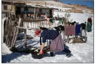  ?? ?? A woman puts out clothes to dry amidst the snow outside her home.