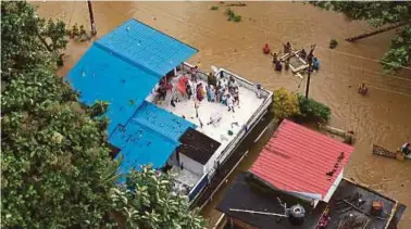  ?? REUTERS PIX ?? People waiting for help on the roof of their flooded house in the state of Kerala yesterday.