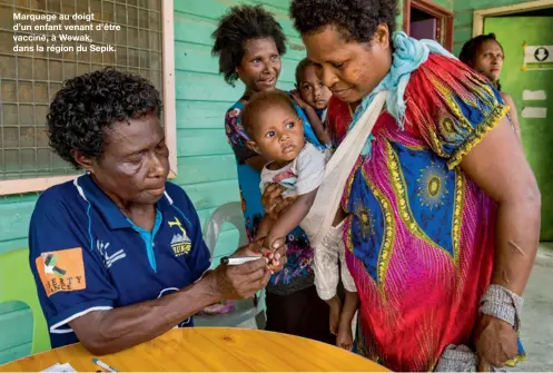  ??  ?? Marquage au doigt d’un enfant venant d’être vacciné, à Wewak, dans la région du Sepik.