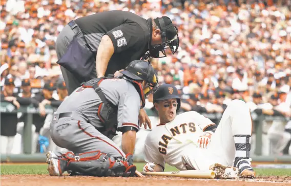  ?? Eric Risberg / Associated Press ?? Giants catcher Buster Posey is looked at by umpire Fieldin Culbreth and Arizona catcher Jeff Mathis after getting hit in the helmet by a fastball Monday.