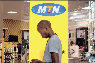  ?? PHOTO: BLOOMBERG ?? A customer uses a smartphone while standing in front of a branded sign inside an MTN Group phone store in Cape Town. MTN problems continue, with a sharp decline of its earnings per share. It blames its never-ending problems in Nigeria and currency...