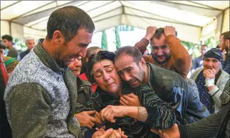  ?? BULENT KILIC / AGENCE FRANCE- PRESSE ?? Relatives of three members of one family — Royal Sahnazarov, his wife Zuleyha and their daughter Medine — mourn at their funeral in the city of Ganja in Azerbaijan on Saturday. They were killed when a rocket hit their home during fighting over Nagorno- Karabakh.