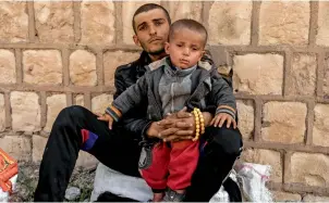  ?? Reuters ?? A displaced Iraqi with his son as he waits to be transporte­d out of the city. —
