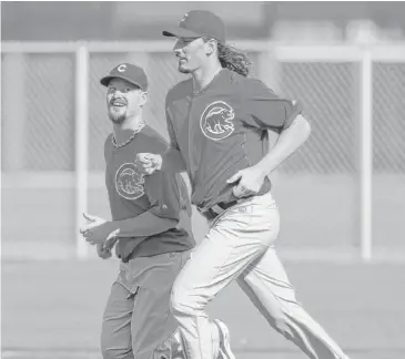  ?? | RICK SCUTERI/AP ?? Starting pitchers Travis Wood (left) and Jeff Samardzija run in the outfield during camp in Mesa, Ariz.