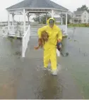  ?? FILE ?? David Van De Graaff carries his dog Kaya in Wachapreag­ue on Virginia’s Eastern Shore during high tide on Oct. 29, 2012.