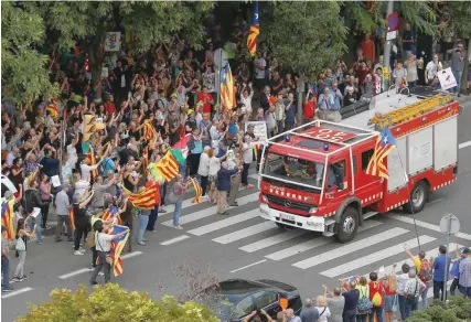  ?? — Reuters ?? People applaud and wave at a passing fire truck during a protest in support of Catalan officials arrested in raids on government offices, outside a courthouse in Barcelona on Friday.