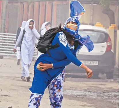  ?? PHOTO: PTI ?? A girl throws a stone at security personnel during clashes in the vicinity of Lal Chowk in Srinagar