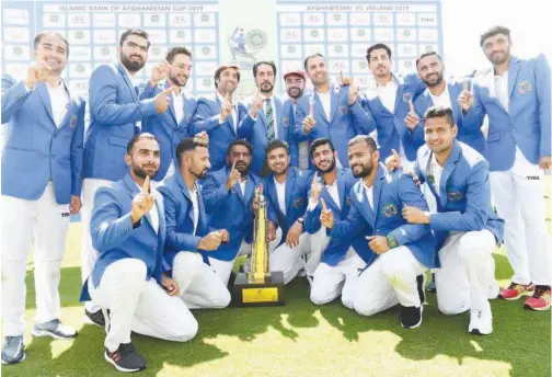  ?? Agence France-presse ?? ↑ The Afghanista­n team pose with the trophy after winning the one-off Test match against Ireland on Monday.