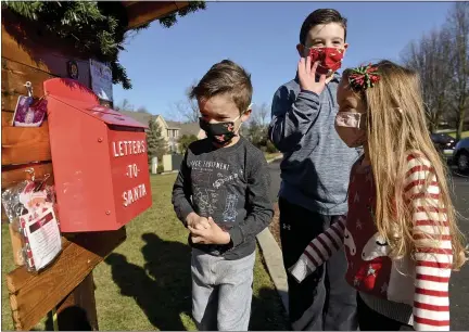  ?? BEN HASTY — MEDIANEWS GROUP PHOTO ?? Park Parsons, 6, his brother Max, 8, and sister Sadie, 4, check the “letters to Santa” mailbox at their home in Exeter Township. Their parents, Amy and Ryan Parsons, process the letters for Santa to reply to them. The family and others are leaving gift cards by the mailbox for those who need them.