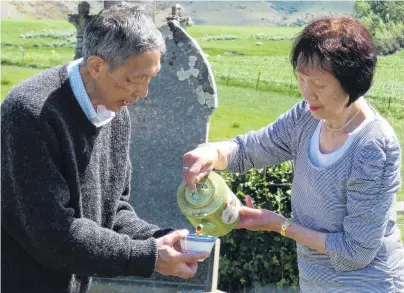 ?? PHOTO: SIMON HENDERSON ?? Paying respects . . . Leslie and Maisie Wong, of Dunedin, perform a Chinese spiritual blessing and prayer at Drybread Cemetery yesterday.