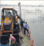  ?? HT PHOTO ?? An excavator clears the lake of nets tied to catch prawns.