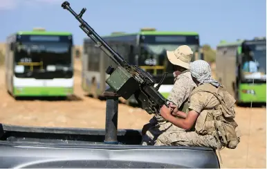  ?? (Ali Hashisho/Reuters) ?? HEZBOLLAH FIGHTERS sit on the back of a truck mounted with an anti-aircraft weapon near the Syria-Lebanon border in August.