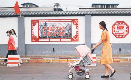  ??  ?? Personas caminando frente a un mural de propaganda a lo largo de una calle de Beijing.