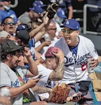  ??  ?? DODGERS FANS enjoy the sunshine and one another in the left-field pavilion seats during the Dodgers’ win over the Washington Nationals. “It feels like L.A. is back,” Mayor Eric Garcetti says.