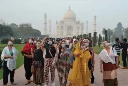  ?? — AFP ?? Foreign tourists wearing face masks visit the Taj Mahal under heavy smog conditions in Agra on Monday.