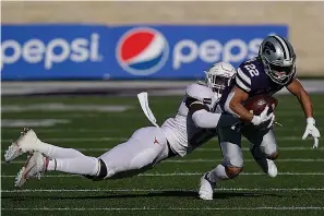  ?? AP Photo/Orlin Wagner ?? ■ Kansas State running back Deuce Vaughn (22) is tackled by Texas linebacker DeMarvion Overshown, left, during the first half of an NCAA college football game Saturday in Manhattan, Kan.