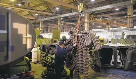  ?? BRAM JANSSEN AP ?? Mechanics move a military vehicle chain track inside a tank workshop in the Kyiv region of Ukraine on Friday.