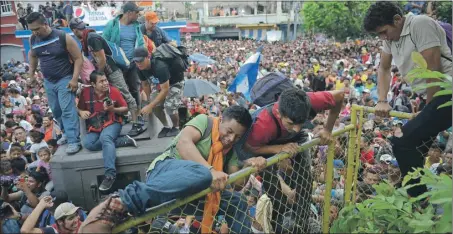  ??  ?? Migrantes hondureños cruzan la frontera sur de México, algunos brincando la valla y enfrentánd­ose a agentes de la Policía Federal, ayer en Tecún Umán, Guatemala