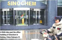  ??  ?? A MAN rides past the office building of Sinochem in Beijing, China February 21.
QUESTIONS AHEAD