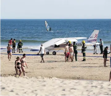  ?? ARMANDO FRANCA / THE ASSOCIATED PRESS ?? People walk past a plane parked by the sea after an emergency landing at Sao Joao beach in Costa da Caparica, Portugal, on Wednesday. The landing on the packed beach killed a man and a child who were sunbathing.