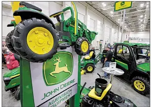  ?? AP ?? John Deere products, including a toy tractor, are displayed last year at a trade show in Council Bluffs, Iowa. Shares of Deere & Co. stocks rose 3.8% Friday after the company pledged to lower costs.