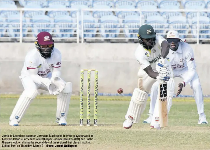  ?? (Photo: Joseph Wellington) ?? Jamaica Scorpions batsman Jermaine Blackwood (centre) plays forward as Leeward Islands Hurricanes wicketkeep­er Jahmar Hamilton (left) and Justin Greaves look on during the second day of the regional first class match at Sabina Park on Thursday, March 21.