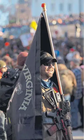  ?? Parker Michels-Boyce, © The New York Times Co. ?? Jeff Balisle stands with his rifle and a modified Virginia state flag at a rally in Richmond, Va. on Monday.