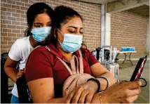  ?? JULIO CORTEZ/ AP ?? Litzi Pop, 8, and her mother, Jaquelyn Morales, of Guatemala wait to be processed Wednesday in Brownsvill­e, Texas. They were stopped while trying to cross the U. S.- Mexico border.