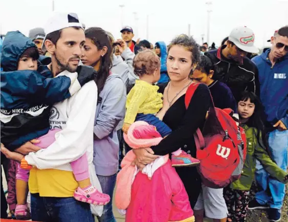  ?? AFP ?? Jorge González y su esposa, Kenia, esperan en fila junto a sus hijos por su desayuno en el centro de atención de la frontera binacional en Tumbes, al norte de Perú, en la frontera con Ecuador. El lugar puede atender a unos 200 viajeros al día, pero actualment­e recibe a más de 2.000.