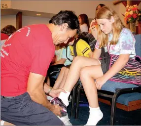  ?? LYNN KUTTER ENTERPRISE-LEADER ?? Jeff Silva with Farmington United Methodist Church helps this young girl try on a pair of new tennis shoes at the Farmington Back to School Bonanza last year. The church is expecting to serve 550-600 children at its 10th Bonanza on Thursday, Aug. 6.