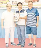  ??  ?? THE WINNER: Andrian Alang claims his prize after winning the Men’s Nett category. Also seen is Tan Sri Bernard Dompok (left) and Willie Wong (right).