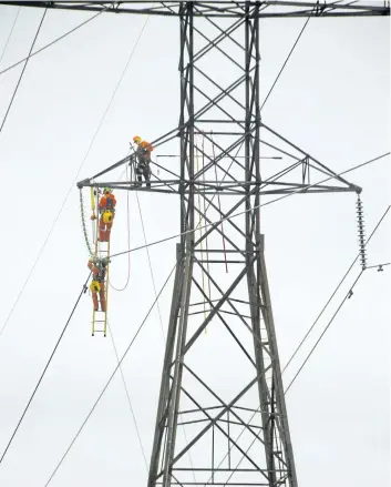  ?? MIKE HENSEN/THE LONDON FREE PRESS ?? Workers from Hydro One work high on a transmissi­on tower east of London, Ont., in February.