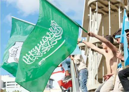  ??  ?? Supporters of Lebanese Prime Minister Saad Hariri wave the Saudi flag alongside the Future Movement flag as they gather at his home in Beirut on Wednesday. (AFP)