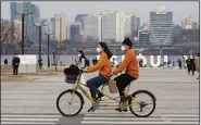  ?? (AP/Ahn Young-joon) ?? Masks and a bicycle built for two are the order of the day Saturday for a couple at a park in Seoul, South Korea. South Korea reported a total of 7,041 coronaviru­s cases Saturday.