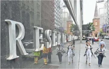  ??  ?? Pedestrian­s are reflected in the wall of the Reserve Bank of Australia in Sydney. — AFP photo