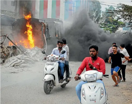  ?? REUTERS ?? Men make their way past a burning truck in Bengaluru during violent protests over a water dispute, which have raised fears about the city’s future as an informatio­n technology centre.