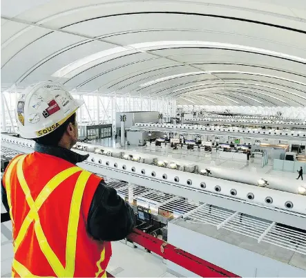  ?? TOBIN GRIMSHAW/THE CANADIAN PRESS ?? An Aecon employee surveys the Toronto airport’s check-in area in this 2003 file photo. Despite the ill effects of the commoditie­s downturn, it could be attractive to bidders based on its record backlog of projects and the robust infrastruc­ture market...