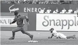  ??  ?? The Diamondbac­ks’ Carson Kelly rounds second base as a ball hit by Jarrod Dyson gets past Rangers second baseman Rougned Odor in the first inning on Wednesday in Arlington, Texas. AP