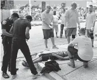  ?? JERRY JACKSON/BALTIMORE SUN ?? Volunteers cleaning up West Baltimore help revive one of two men who had apparently overdosed on the same block on which they were working.