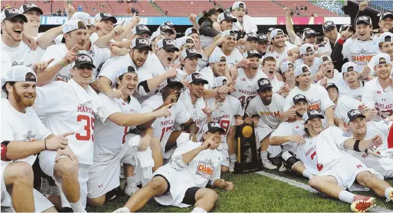  ?? STAFF PHOTO BY CHRISTOPHE­R EVANS ?? LONG WAIT WORTH IT: Maryland players pose on the Gillette Stadium turf with the NCAA trophy after the Terrapins won their first men’s lacrosse national championsh­ip since 1975, capping it with yesterday’s 9-6 victory against Ohio State.