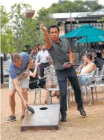  ?? Karen Warren / Houston Chronicle ?? James Zhao throws a bean bag as David Skahn, left, reaches for another during a round of cornhole on the patio at Heights Bier Garten. Many of the city’s buzziest patios are keeping patrons engaged with a variety of games.