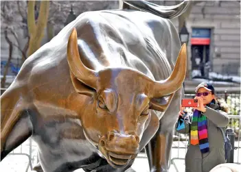  ?? — AFP photo ?? A woman takes a selfie with the ‘Charging Bull’ statue in New York City.