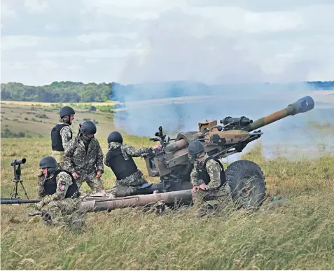  ?? ?? Members of the Ukrainian armed forces are shown how to operate L119 Light Guns by the British Army